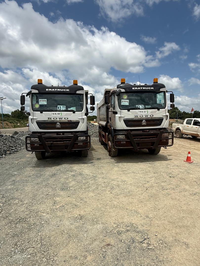 Deux camions benne SINOTRUK de Koswende Services stationnés sur une plateforme de mine